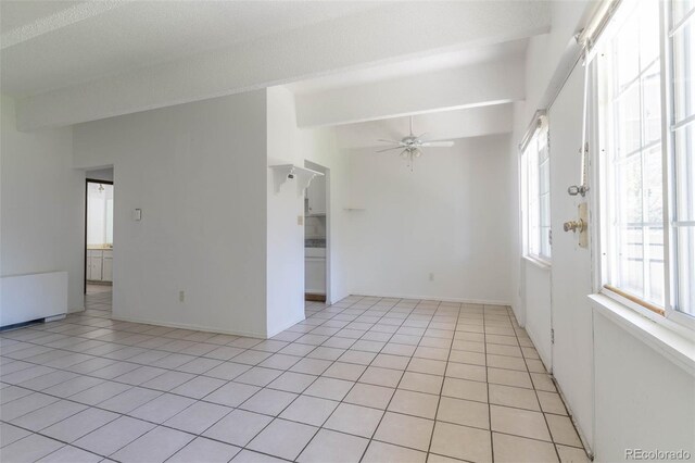 tiled empty room featuring ceiling fan, radiator heating unit, and lofted ceiling with beams