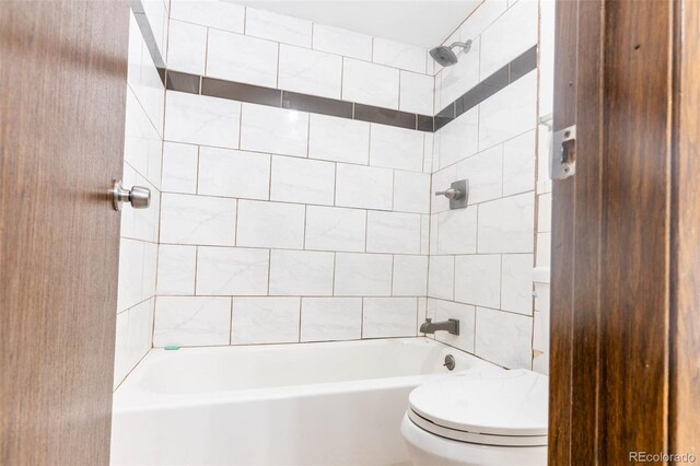 bathroom with tiled shower / bath combo and toilet