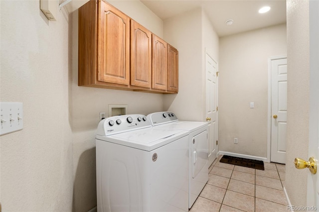 washroom featuring cabinets, light tile patterned flooring, and washing machine and clothes dryer