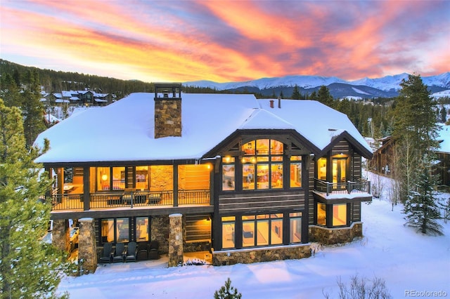 snow covered rear of property featuring a mountain view and a balcony