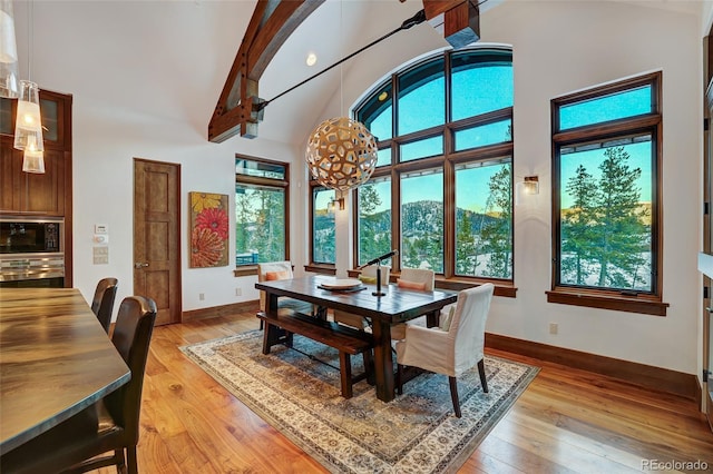 dining area featuring light wood-type flooring, a wealth of natural light, and high vaulted ceiling