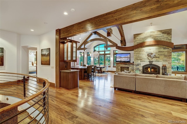 living room featuring lofted ceiling with beams, plenty of natural light, light wood-type flooring, and a fireplace