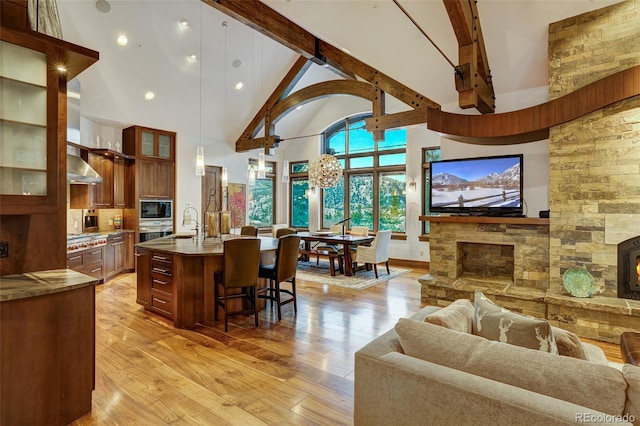 kitchen featuring a kitchen bar, hanging light fixtures, a kitchen island with sink, stainless steel appliances, and light hardwood / wood-style floors