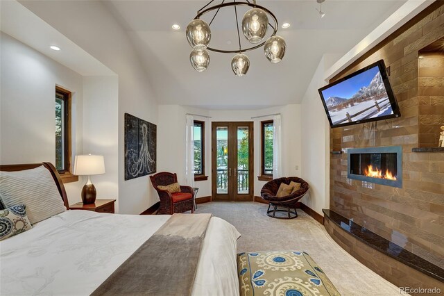 carpeted bedroom with lofted ceiling, access to exterior, a tiled fireplace, french doors, and a chandelier