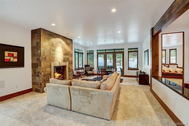 living room with french doors, a stone fireplace, and light carpet