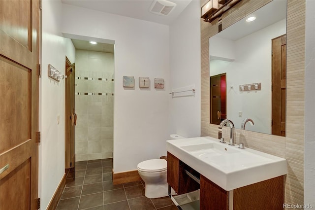 bathroom featuring walk in shower, vanity, tile patterned floors, and toilet