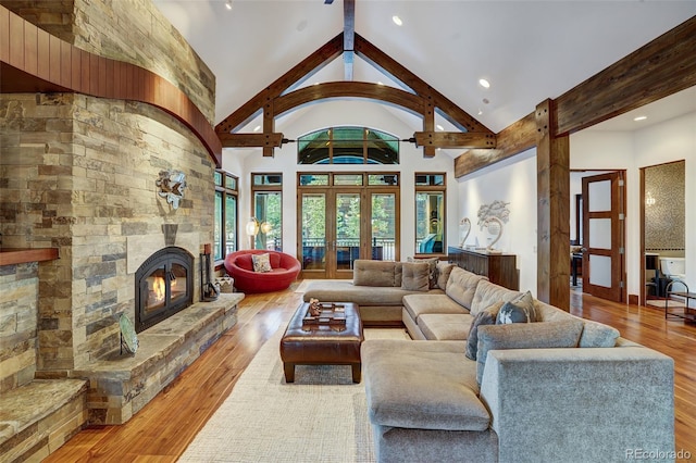 living room featuring high vaulted ceiling, hardwood / wood-style floors, a fireplace, and french doors