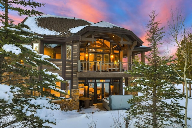 snow covered back of property with french doors and a balcony