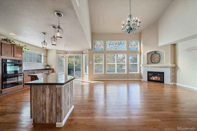 6317 Ruby Hill Dr, Erie, CO 80516 - kitchen featuring an inviting chandelier, dark countertops, dobule oven black, and dark wood-type flooring