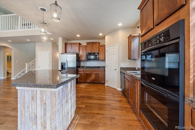 6317 Ruby Hill Dr, Erie, CO 80516 - kitchen featuring pendant lighting, arched walkways, brown cabinets, wood finished floors, and black appliances