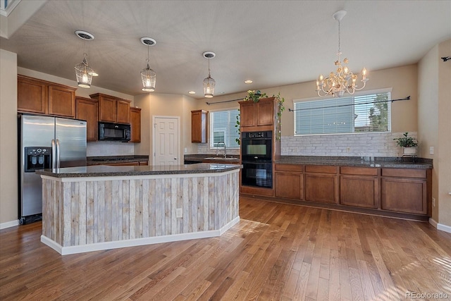 6317 Ruby Hill Dr, Erie, CO 80516 - kitchen with decorative backsplash, brown cabinets, black appliances, light wood-style floors, and a wealth of natural light