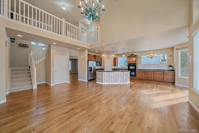 6317 Ruby Hill Dr, Erie, CO 80516 - unfurnished living room featuring a notable chandelier, light wood finished floors, stairs, baseboards, and a towering ceiling