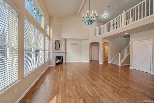 6317 Ruby Hill Dr, Erie, CO 80516 - unfurnished living room with arched walkways, light wood-style flooring, a notable chandelier, and a wealth of natural light
