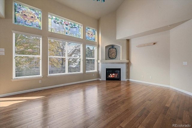 6317 Ruby Hill Dr, Erie, CO 80516 - unfurnished living room with baseboards, a healthy amount of sunlight, hardwood / wood-style flooring, and a towering ceiling