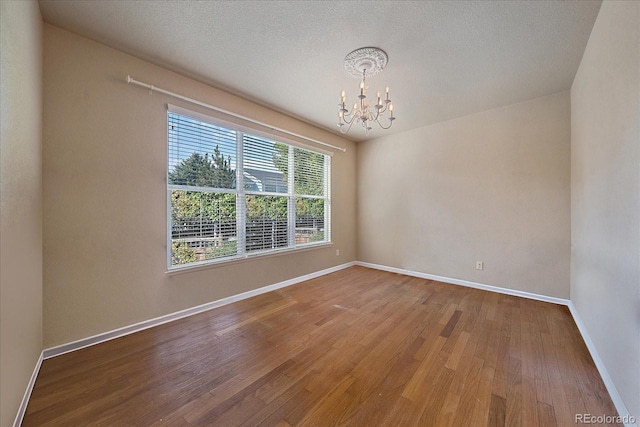 6317 Ruby Hill Dr, Erie, CO 80516 - empty room featuring an inviting chandelier, baseboards, and wood finished floors