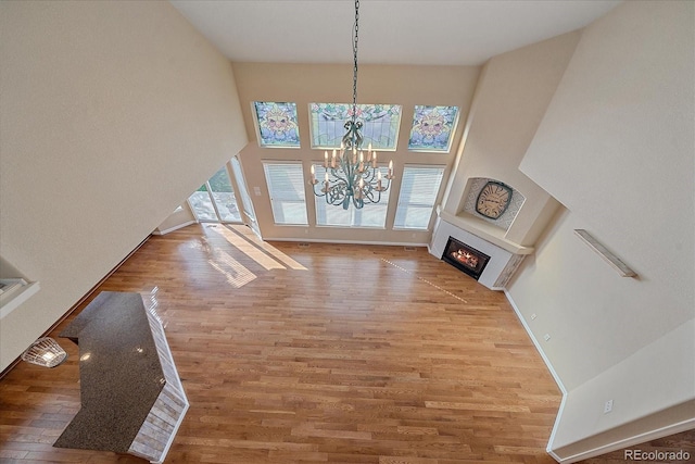 6317 Ruby Hill Dr, Erie, CO 80516 - unfurnished dining area featuring a towering ceiling, wood finished floors, baseboards, a notable chandelier, and a glass covered fireplace