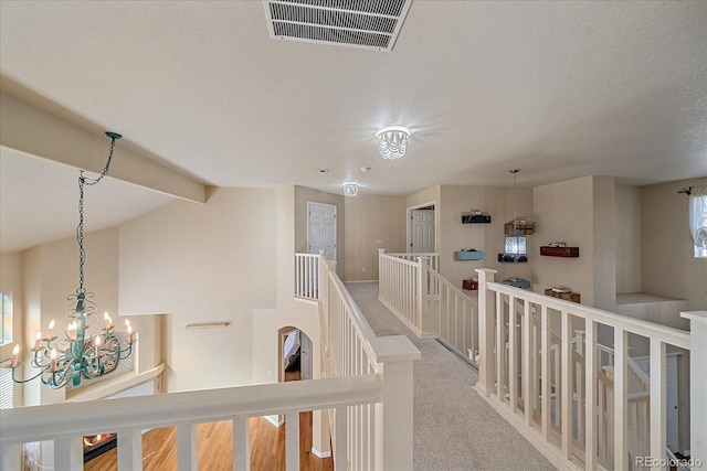 6317 Ruby Hill Dr, Erie, CO 80516 - hallway featuring a textured ceiling, a chandelier, carpet, an upstairs landing, and visible vents