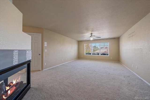 6317 Ruby Hill Dr, Erie, CO 80516 - unfurnished living room featuring carpet flooring, a ceiling fan, a textured ceiling, and a tiled fireplace