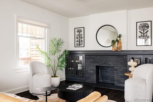 living area with a brick fireplace, wood finished floors, and baseboards