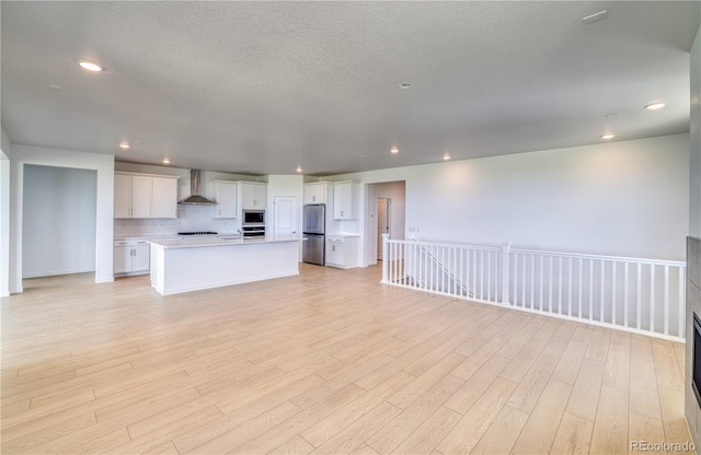 unfurnished living room with a textured ceiling and light wood-type flooring