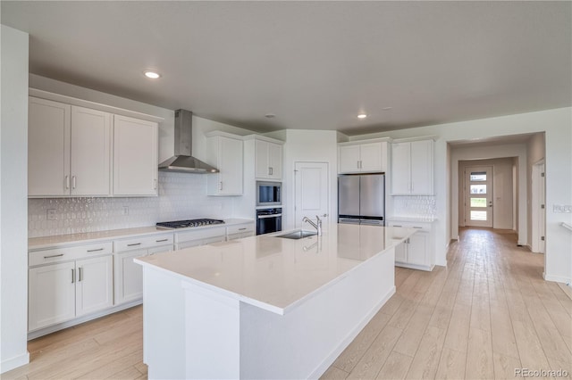 kitchen featuring white cabinetry, wall chimney range hood, and stainless steel appliances