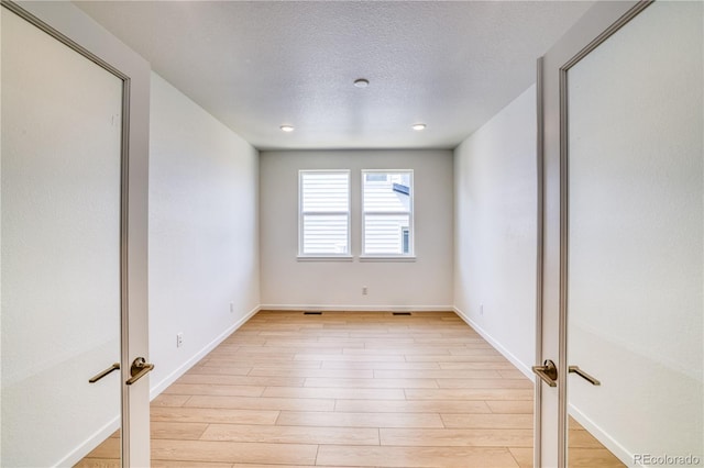 unfurnished room featuring a textured ceiling and light wood-type flooring