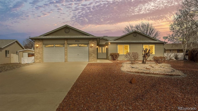 ranch-style house featuring a garage, concrete driveway, brick siding, and fence