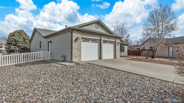 garage with concrete driveway and fence