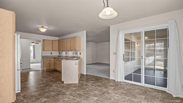 kitchen with light brown cabinets, a peninsula, a sink, freestanding refrigerator, and decorative light fixtures