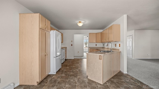 kitchen with a baseboard radiator, a peninsula, range with electric stovetop, a sink, and freestanding refrigerator