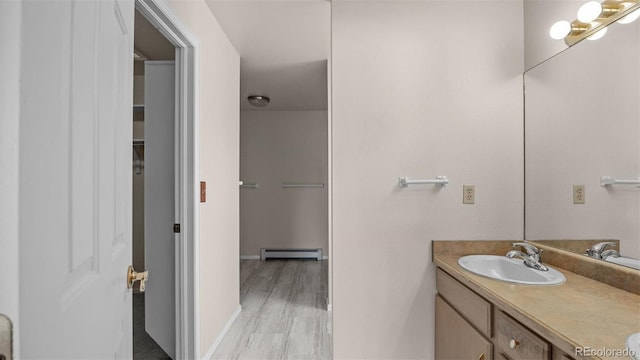 bathroom featuring a baseboard radiator, vanity, baseboards, and wood finished floors