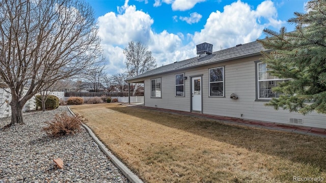 rear view of property featuring fence and a lawn