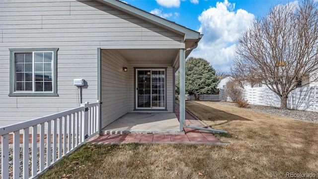 doorway to property featuring a patio area, fence, and a lawn