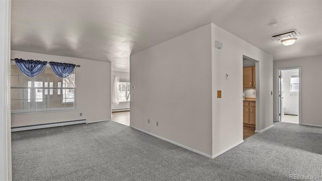 carpeted empty room with a baseboard radiator, visible vents, and baseboards