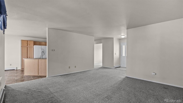 unfurnished living room featuring a baseboard heating unit, carpet flooring, and baseboards