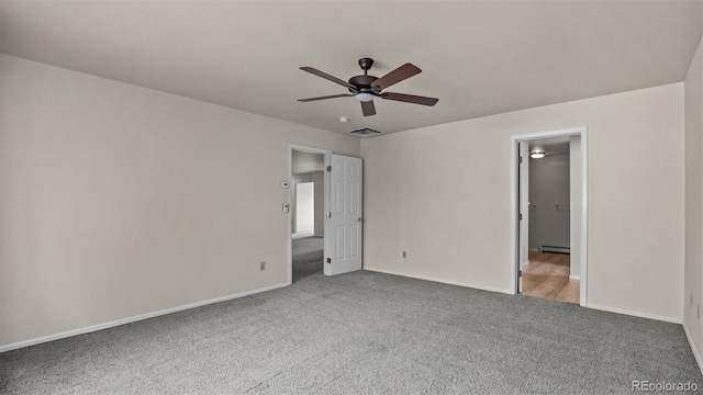 unfurnished bedroom with carpet floors, visible vents, a baseboard heating unit, a ceiling fan, and baseboards