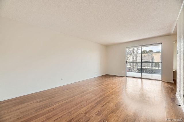 unfurnished room with light wood-style flooring, baseboards, and a textured ceiling