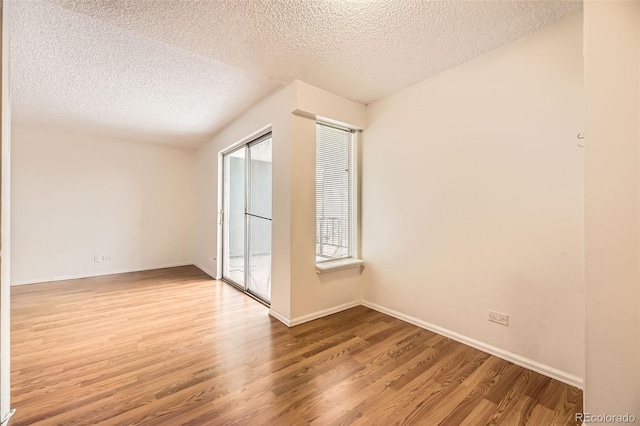 empty room featuring baseboards, wood finished floors, and a textured ceiling
