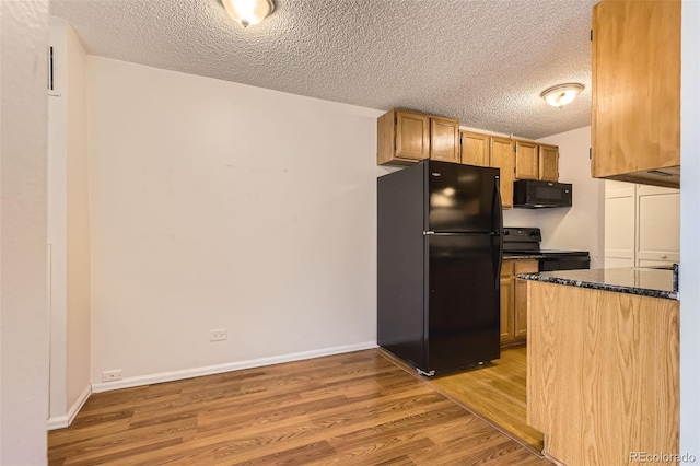 kitchen with a textured ceiling, light wood-style flooring, dark stone countertops, baseboards, and black appliances