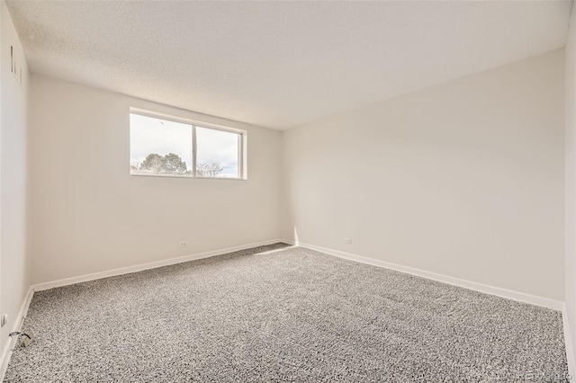 spare room with baseboards, carpet, and a textured ceiling