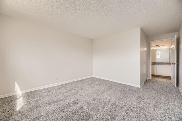 spare room with baseboards, a textured ceiling, and light colored carpet