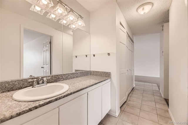 bathroom featuring tile patterned flooring, vanity, baseboards, and a textured ceiling