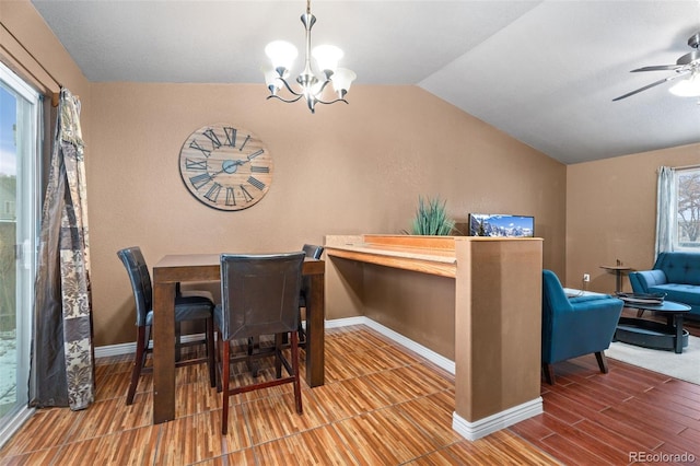 dining space with hardwood / wood-style floors, ceiling fan with notable chandelier, and vaulted ceiling