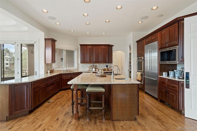 kitchen with built in appliances, a center island, sink, and a breakfast bar area