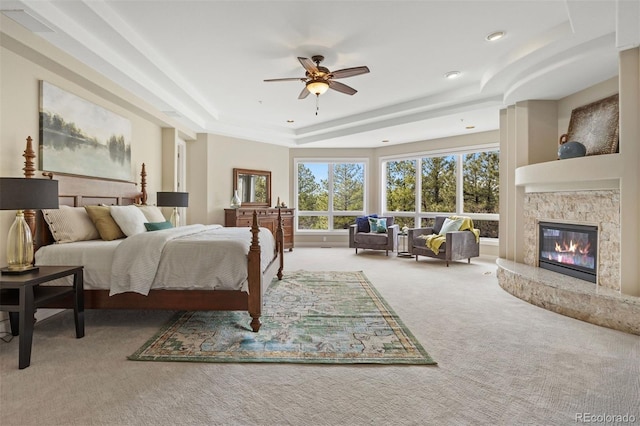 carpeted bedroom with a raised ceiling and ceiling fan