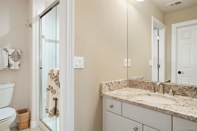 bathroom with vanity, toilet, and a shower with door