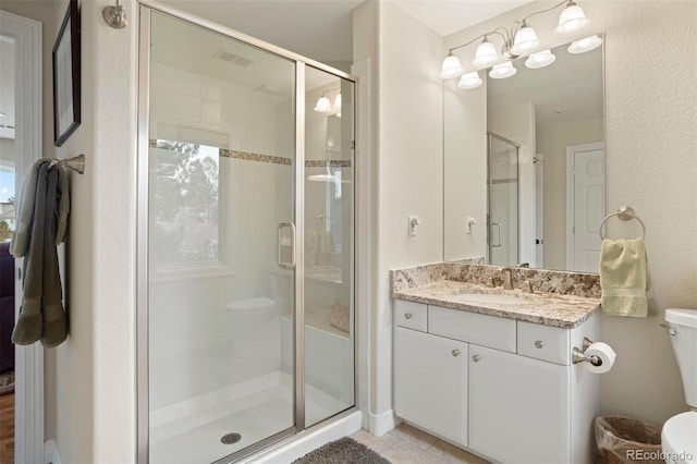 bathroom featuring an enclosed shower, vanity, tile patterned flooring, and toilet