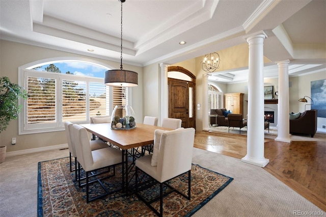 dining space featuring a tray ceiling and ornate columns