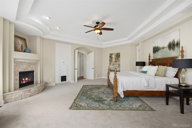 carpeted bedroom featuring a raised ceiling and ceiling fan