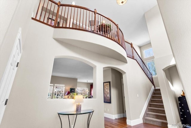 4236 Frederick Cir, Longmont, CO 80503 - stairway with a towering ceiling, arched walkways, baseboards, and wood finished floors